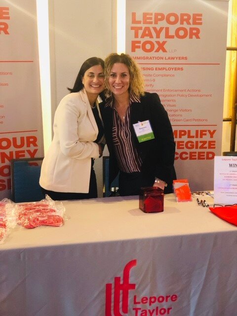 Rosanna and Filomena standing behind a booth, smiling.