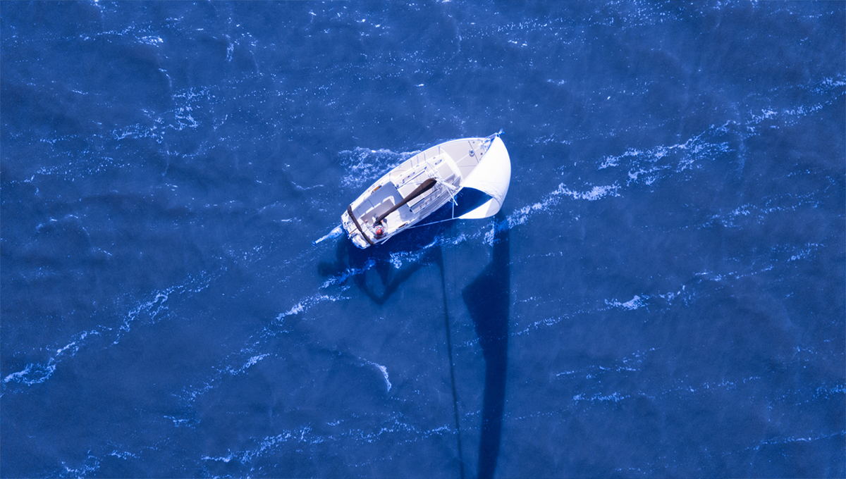 A bird's eye view of a boat in the middle of vast, blue waters.